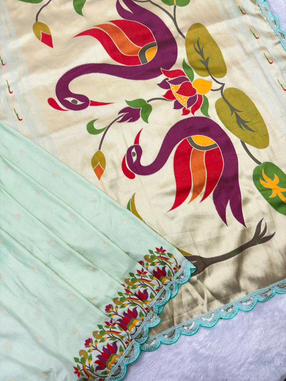 Colorful Light green embroiderey fabric with peacock design on a light blue background