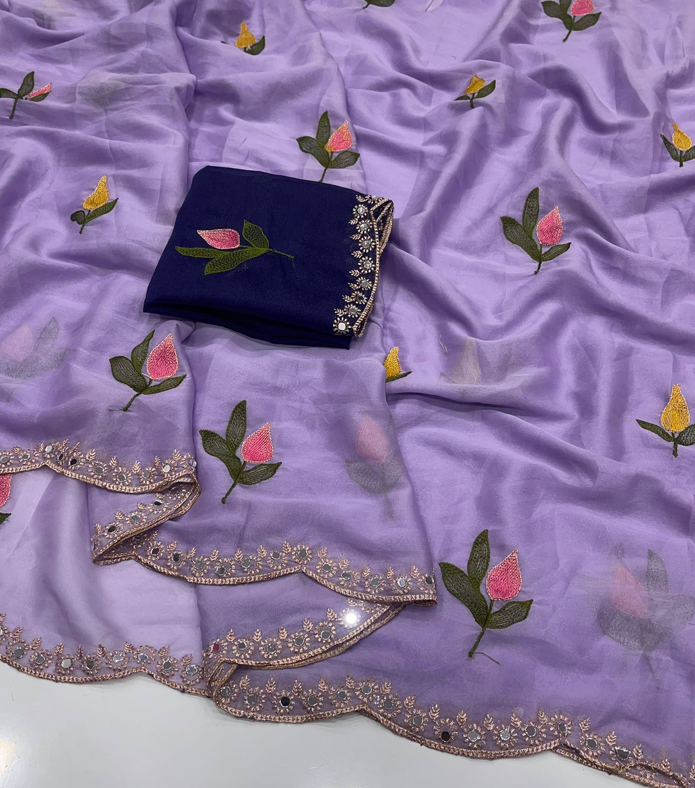 Purple fabric with floral embroidery and a navy blue clutch on a matching background