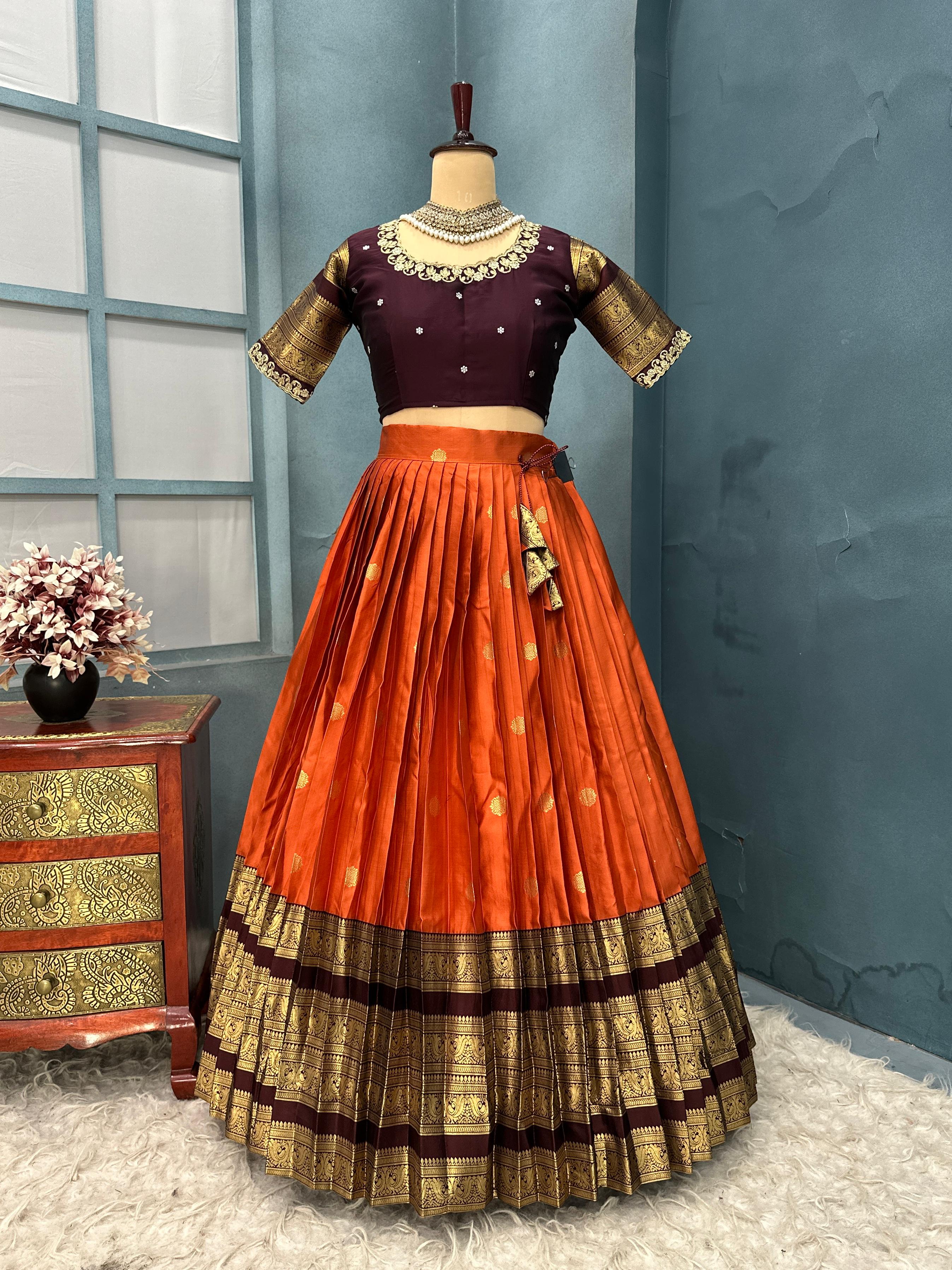 Traditional outfit with orange skirt and purple blouse on a mannequin against a blue wall.