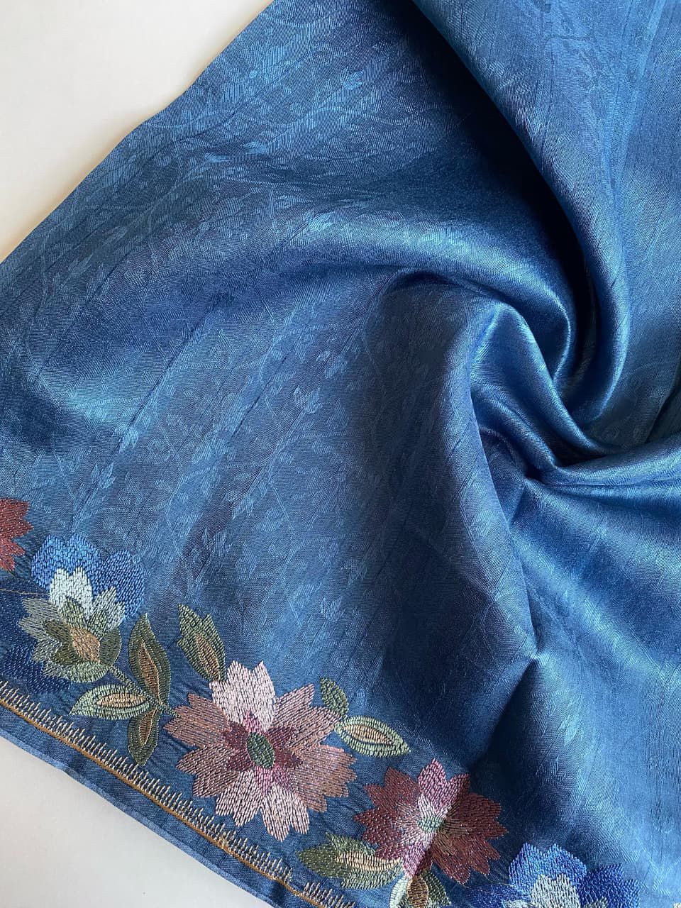 Blue fabric with floral embroidery on a white background