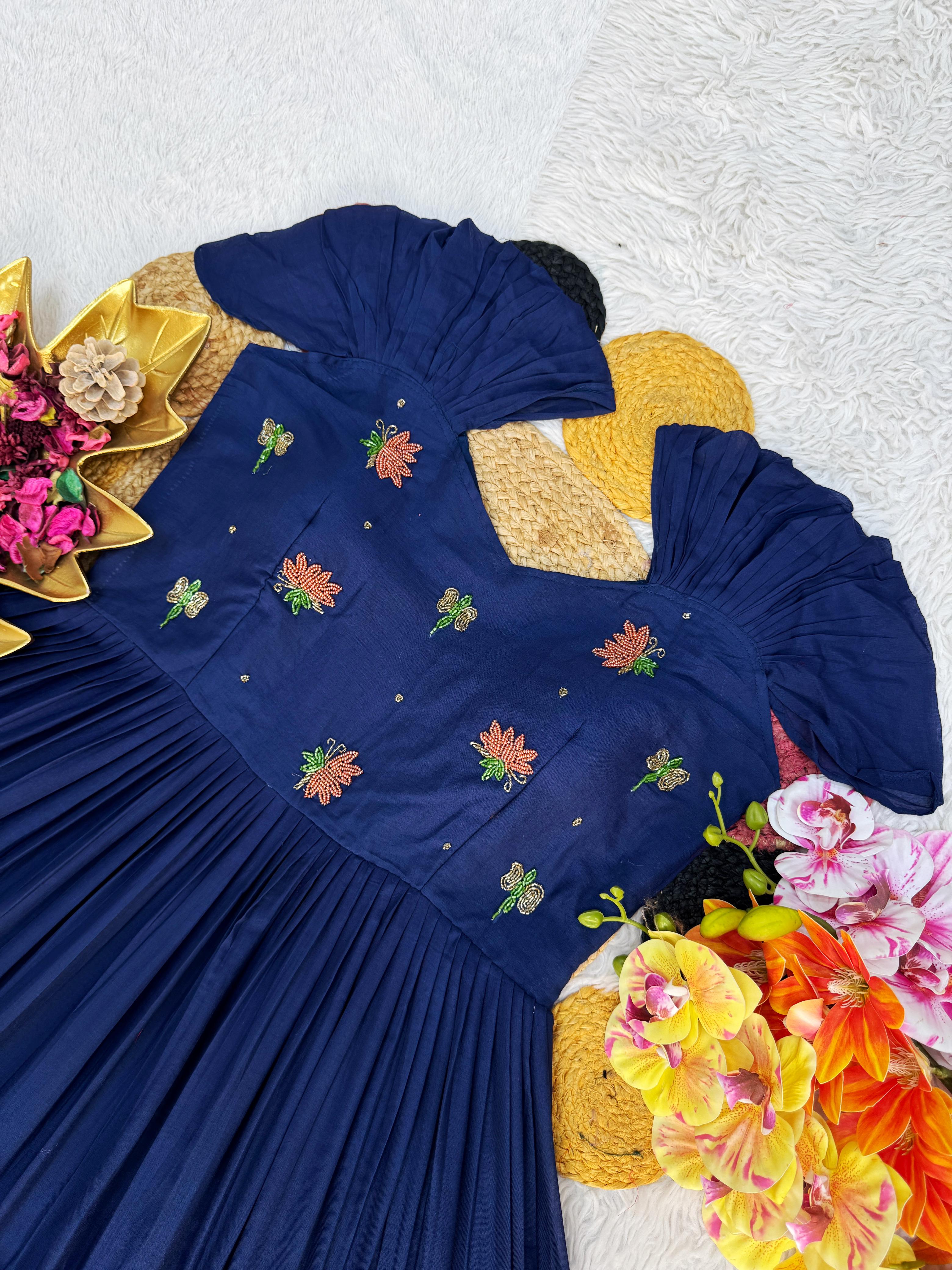 Navy blue dress with floral embroidery on a textured white background with colorful flowers.
