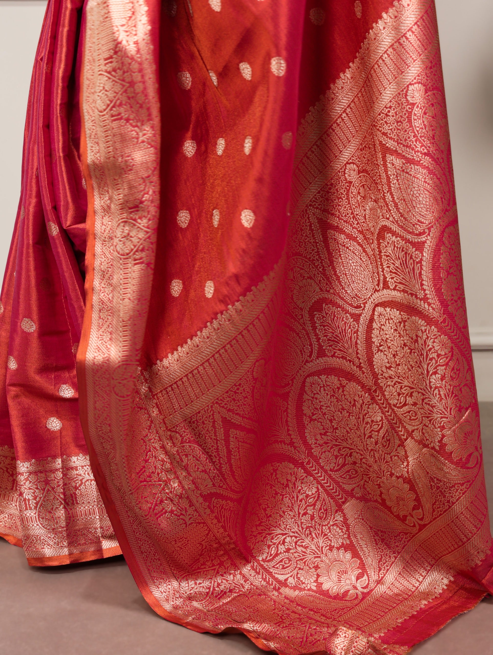 Red saree with gold patterns on a neutral background