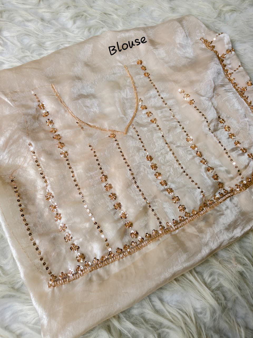 Cream blouse with intricate beadwork on a textured surface