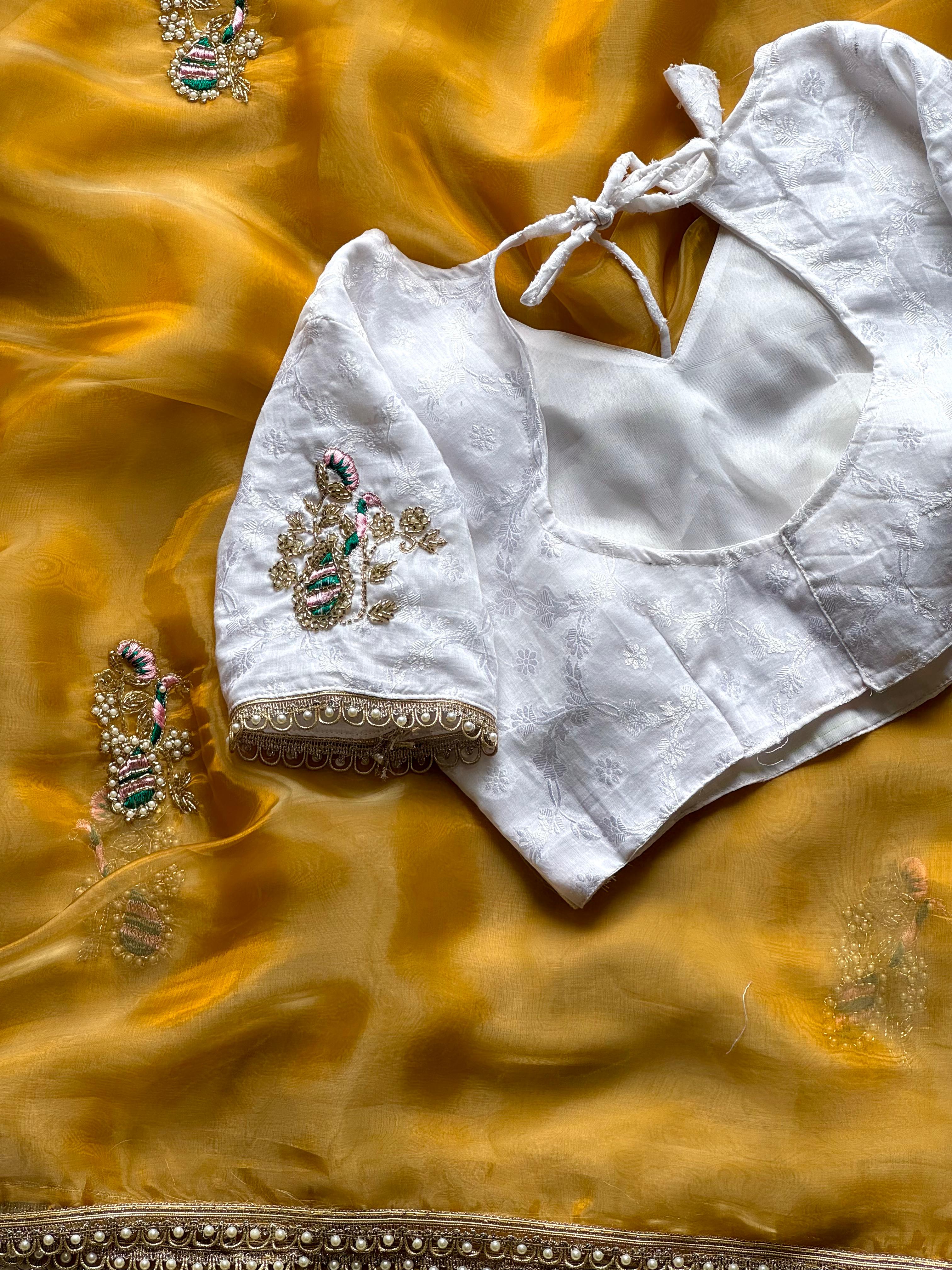 White embroidered blouse with  detailing on a mustard yellow fabric background