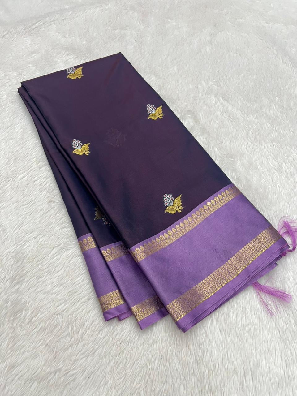 Purple saree with gold border and patterns on a light gray background