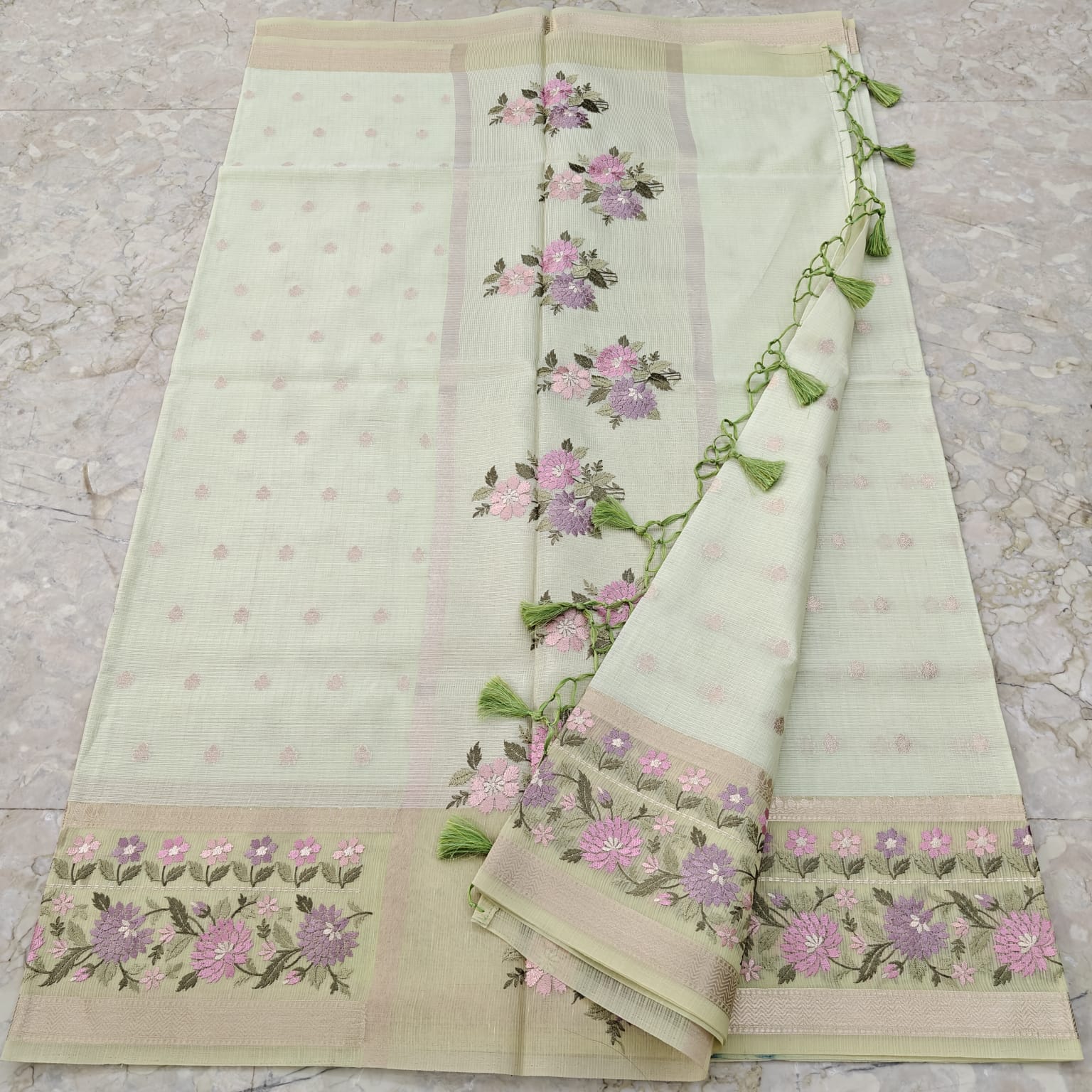 Light pista green fabric with floral embroidery on a textured surface