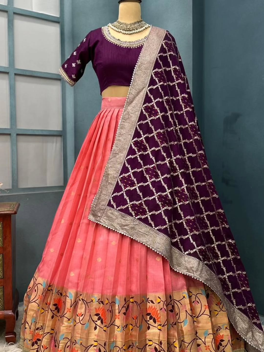 Peach Traditional Indian outfit on a mannequin against a blue wall.
