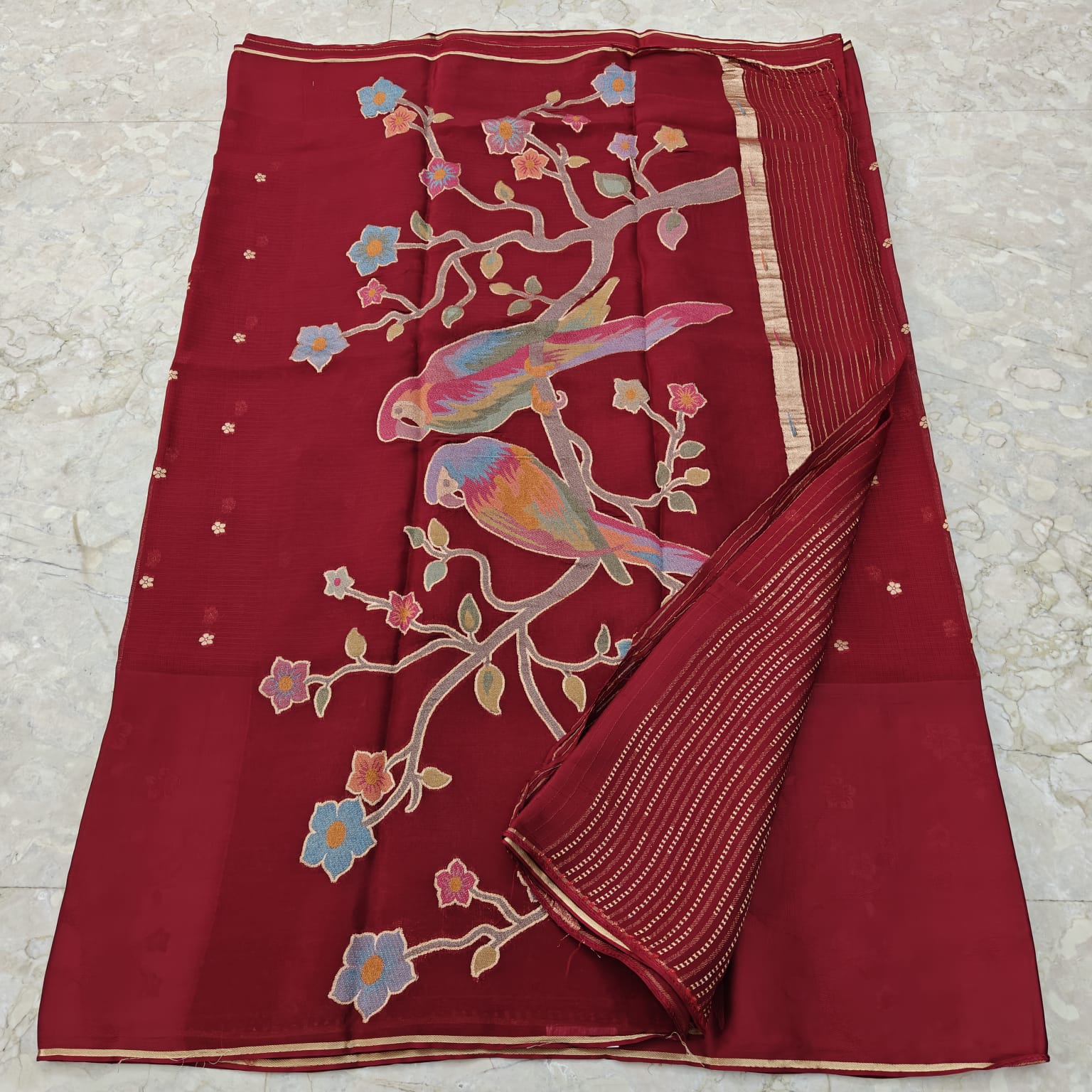 Maroon fabric with colorful bird and floral patterns 