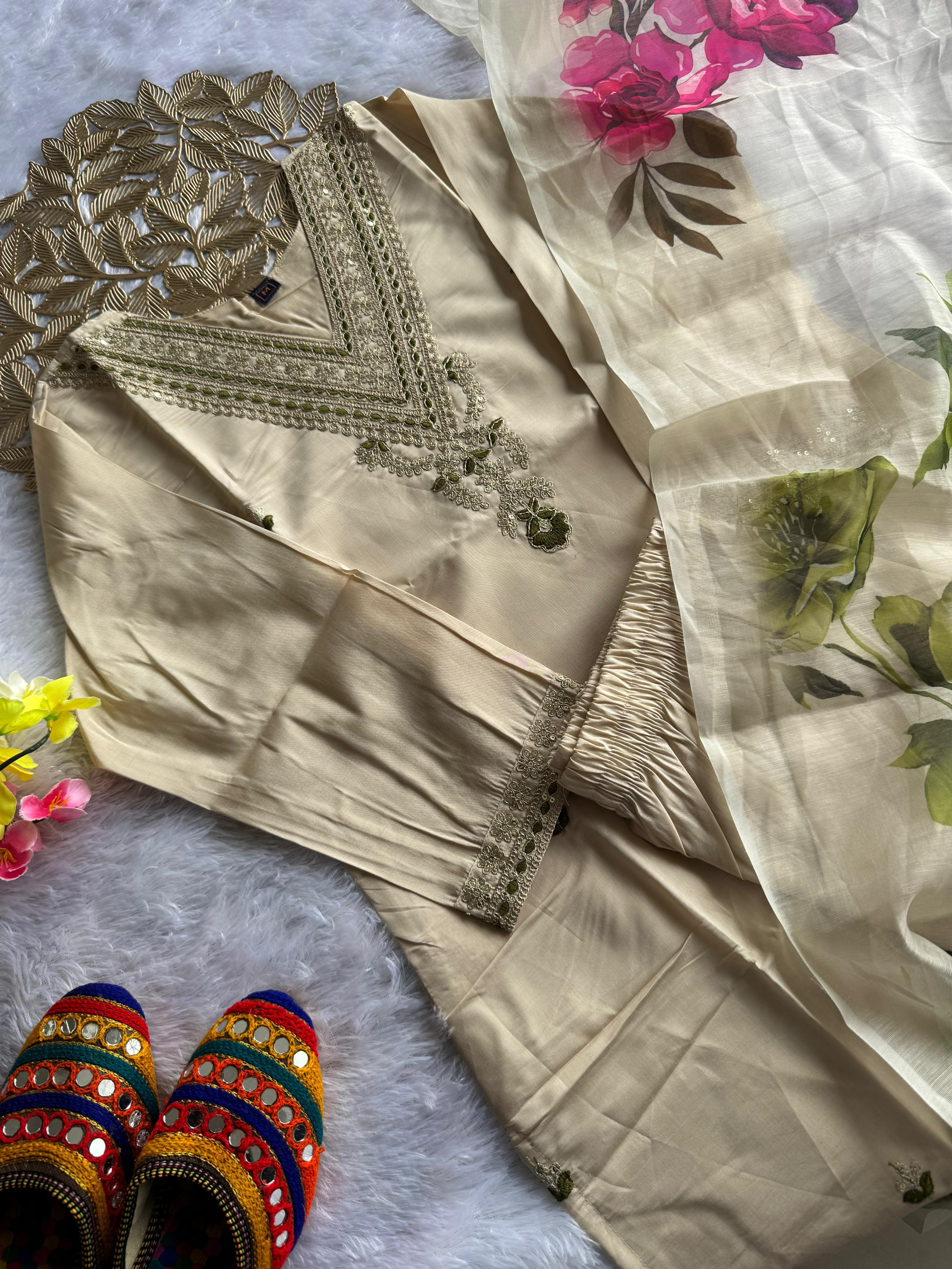 Beige embroidered outfit with floral fabric and colorful slippers on a light background