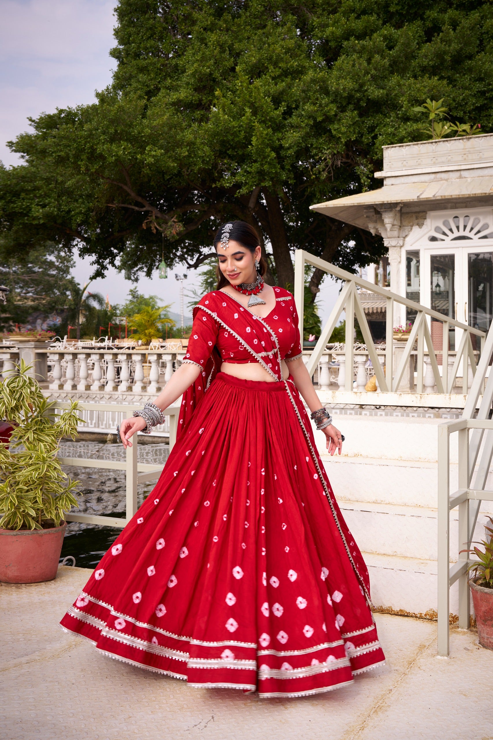 Woman in a red traditional outfit with white patterns standing outdoors.