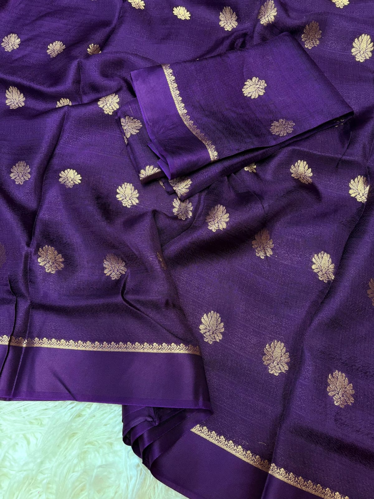 Purple fabric with gold floral patterns on a light background