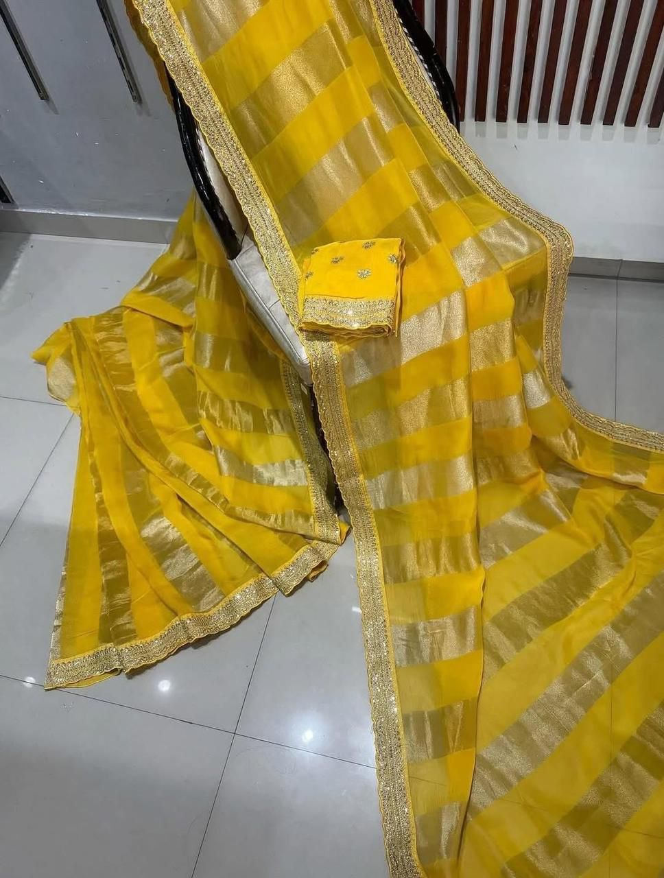Yellow saree with gold border on a tiled floor