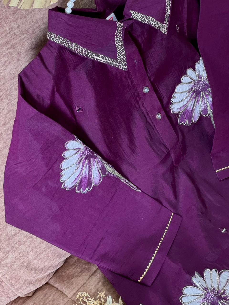 Purple traditional outfit with floral embroidery on a texture surface