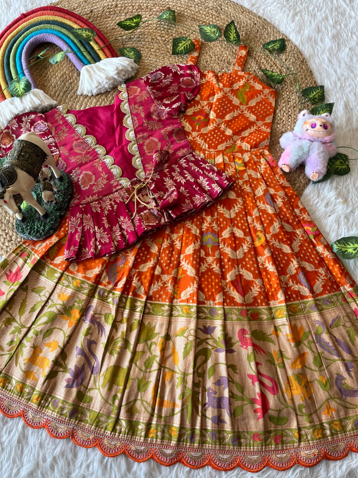 Colorful orange dress with patterns and toys on a texture surface