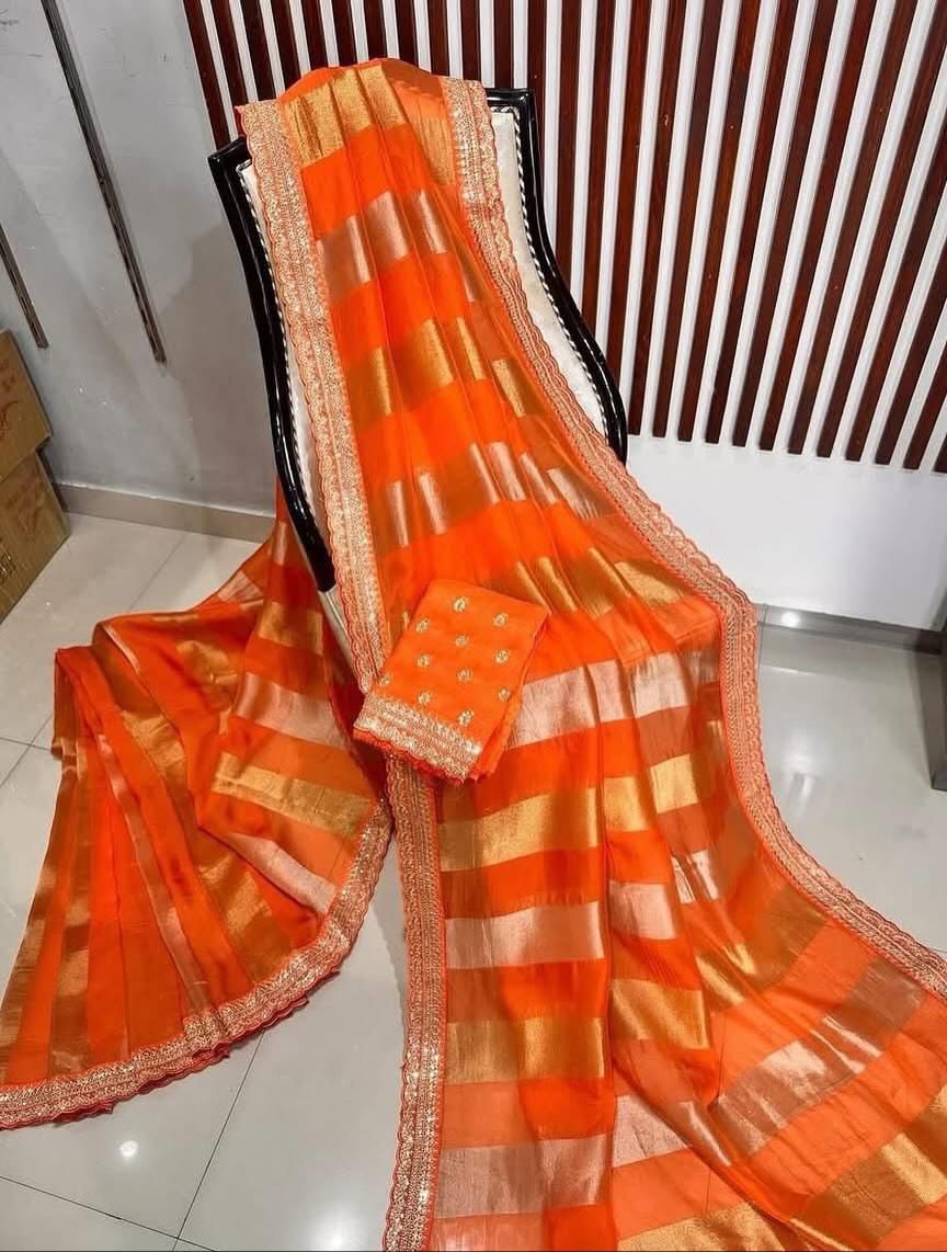 Orange saree with gold patterns draped over a chair indoors.