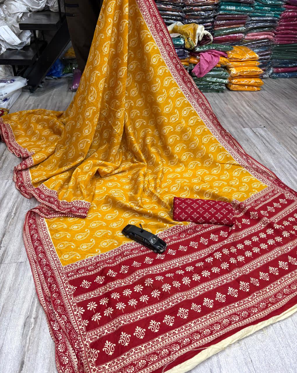 Yellow saree with white patterns on a wooden floor.