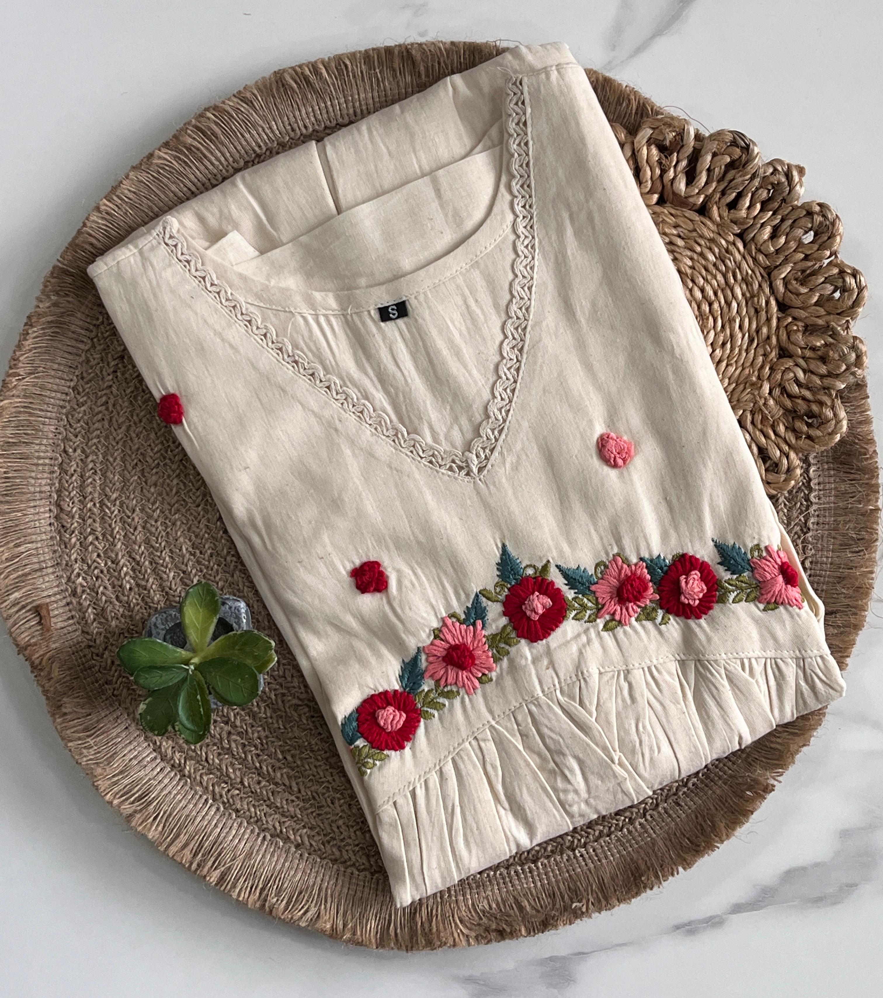 Beige 1 top with floral embroidery on a woven mat