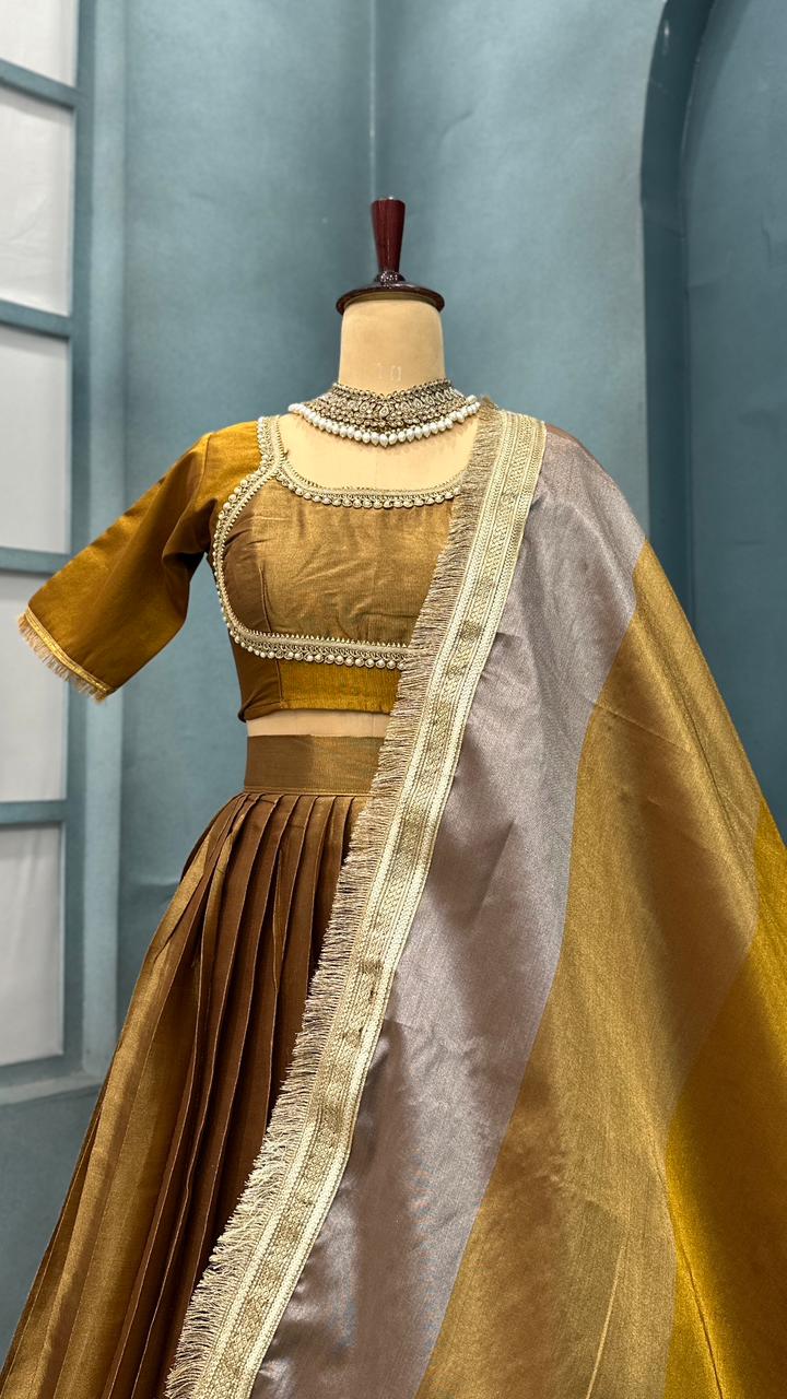 Gold and brown Traditional Indian saree with blouse on a mannequin against a blue wall.