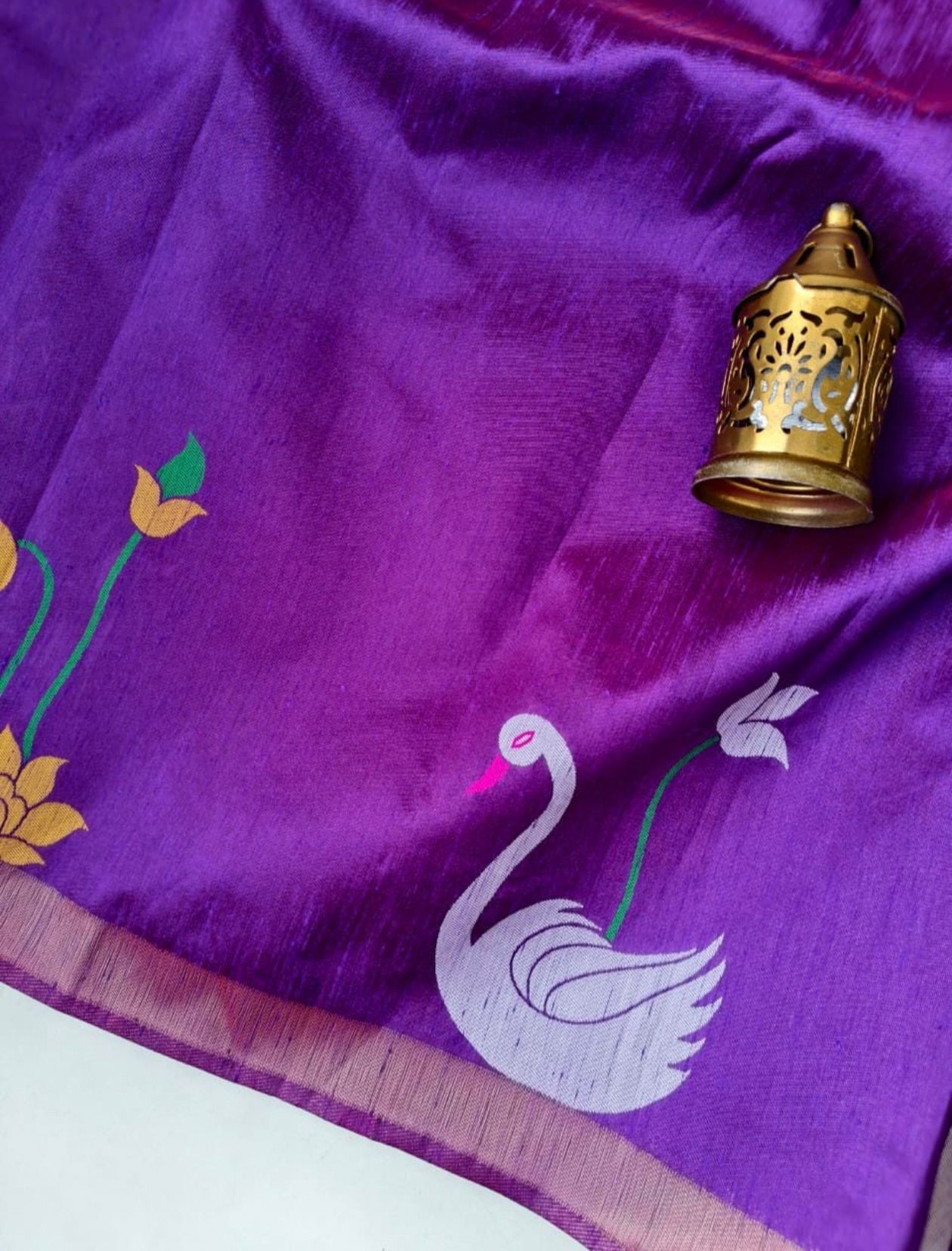 Purple fabric with white swan design and gold decorative item on a white background