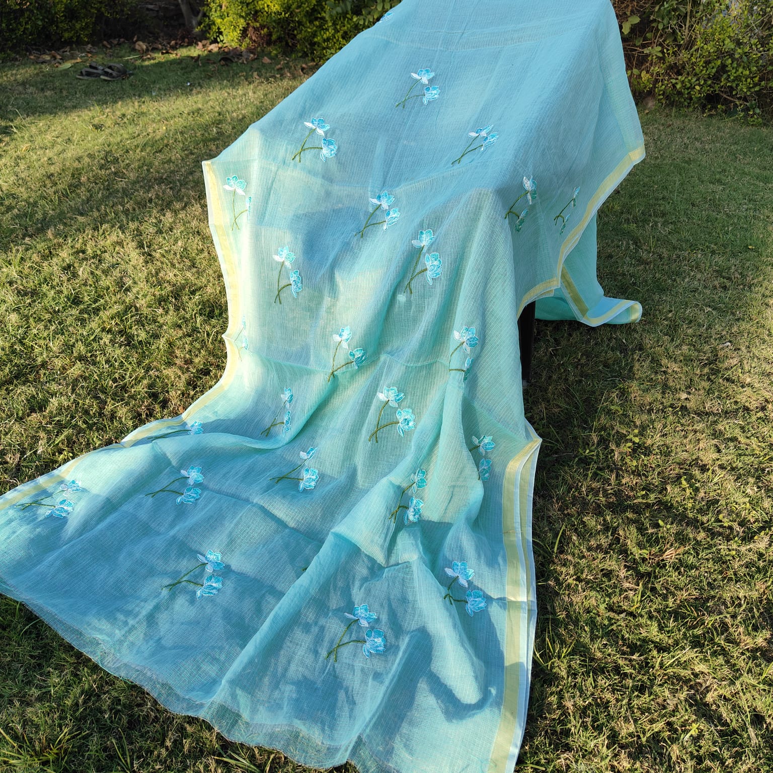 Light blue embroidered fabric on a grassy background