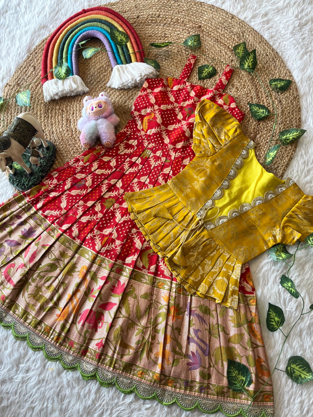 Colorful Red dress with a rainbow, teddy bear, and decorative elements on a textured surface.