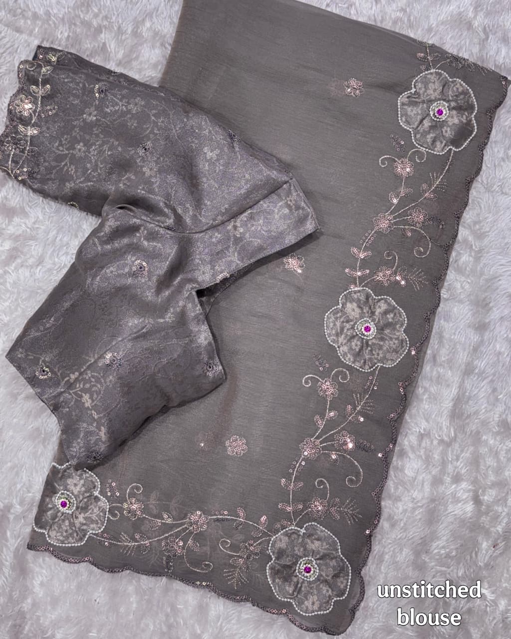 gray saree and unstitched blouse with floral embroidery on a textured surface