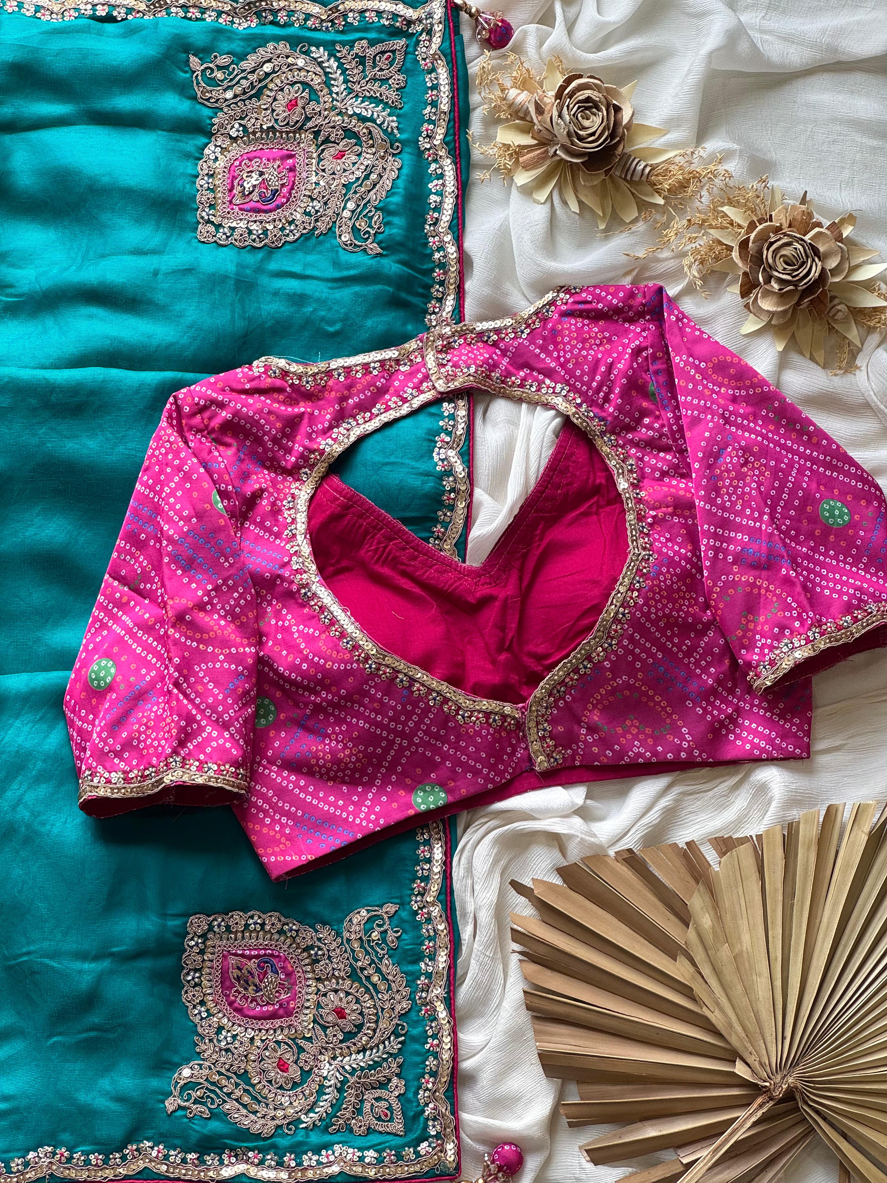 Pink embroidered blouse on a teal blue fabric background with flowers and a fan.