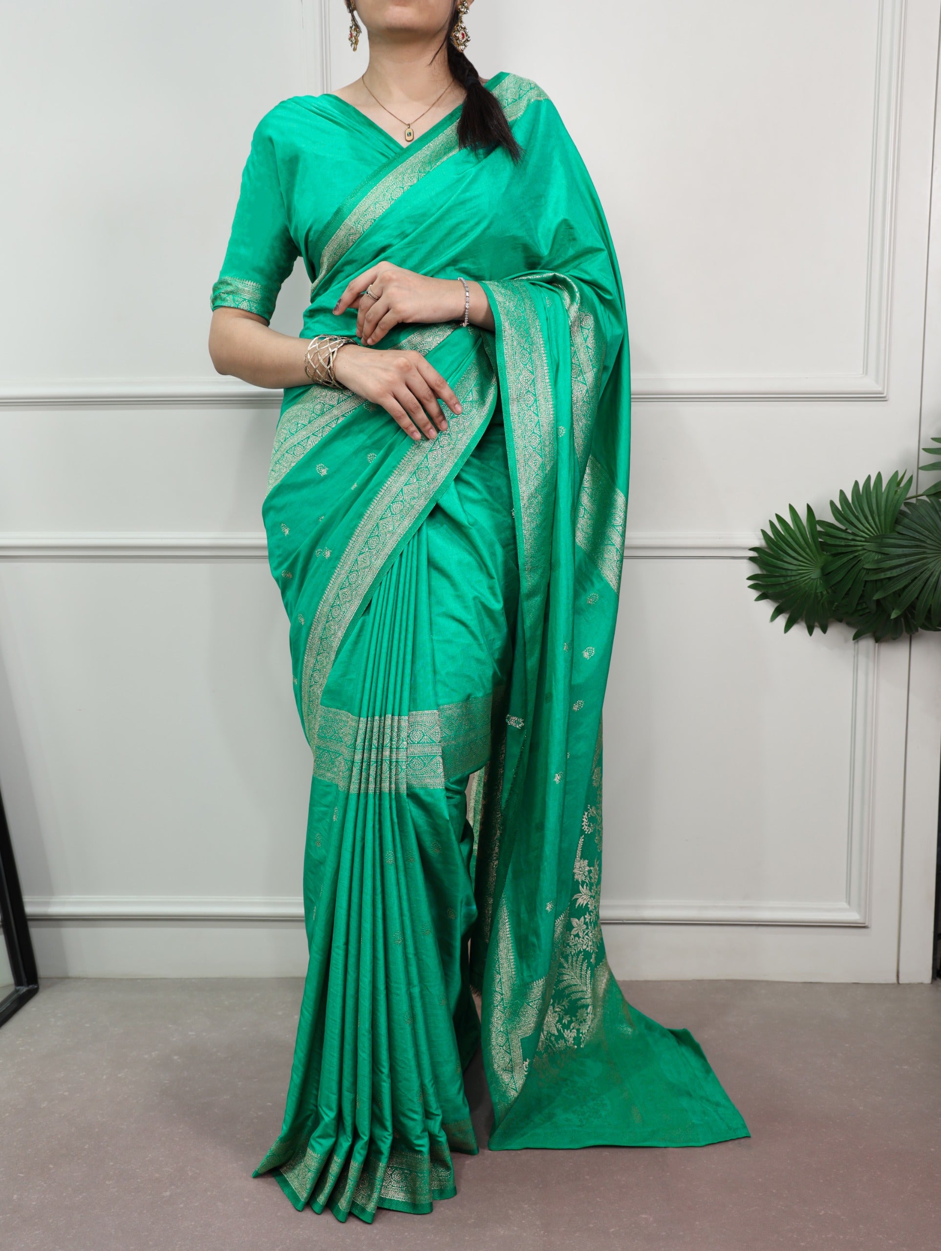 Cyan saree with white border worn by a person against a white wall.