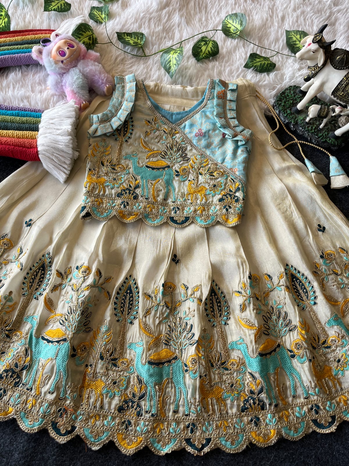 Beige Embroidery dress with deer pattern on a textured surface with toys and decorations.