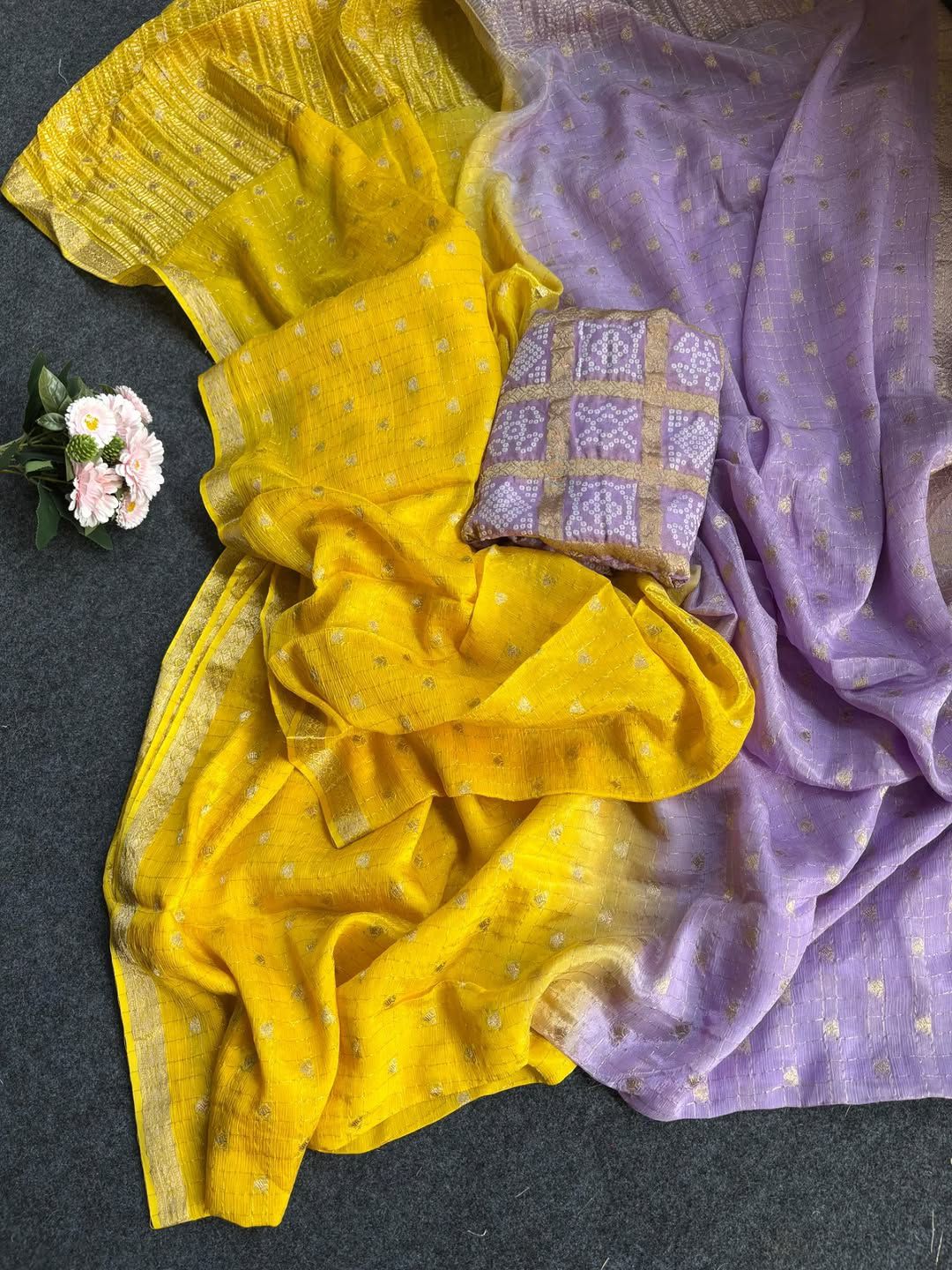 Yellow sarees with a small pillow on a dark surface.