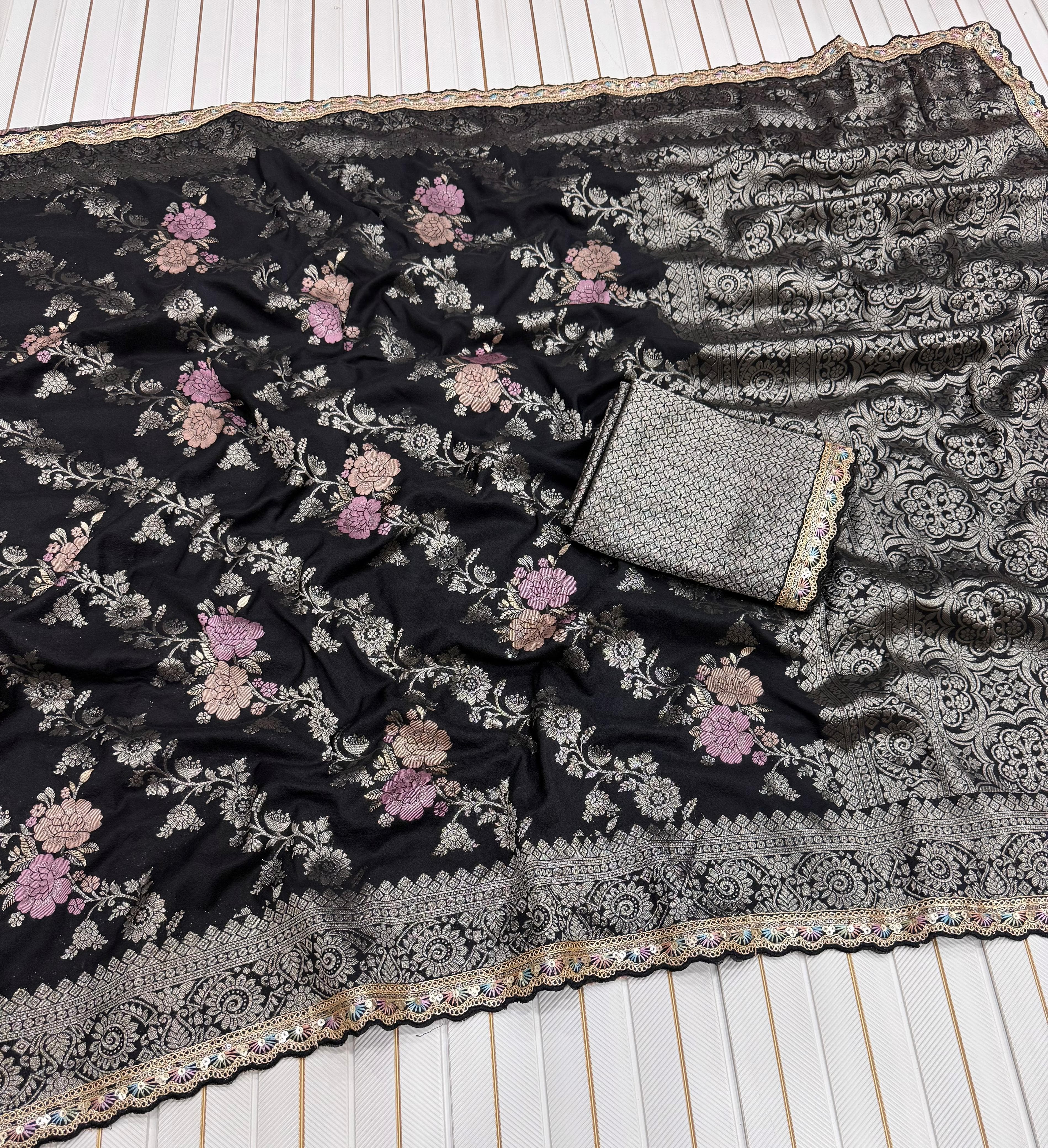 Black floral embroidered fabric with a silver clutch on a wooden surface