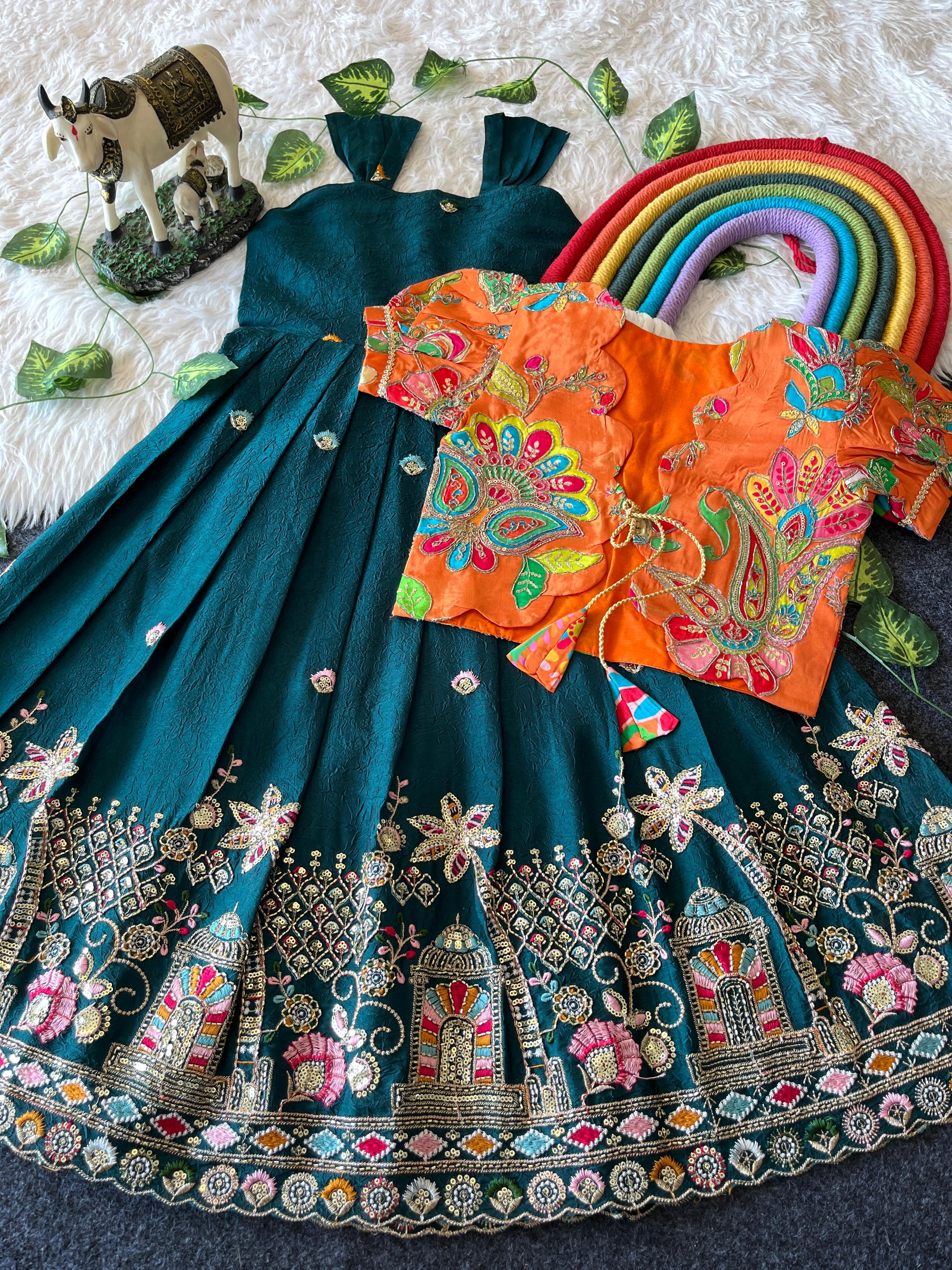 Traditional Rama Green embroidered outfit with a skirt and orange blouse on a textured surface.