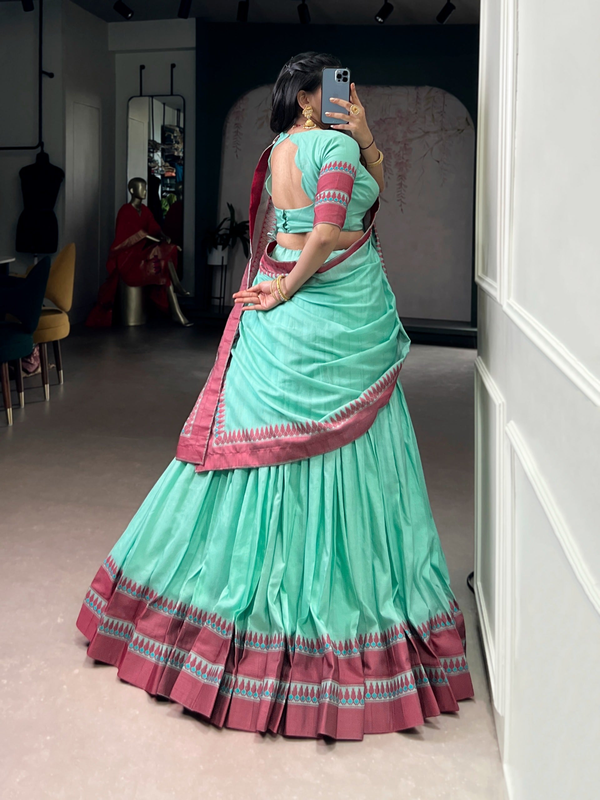 Person wearing a cyan saree with pink border taking a mirror selfie.