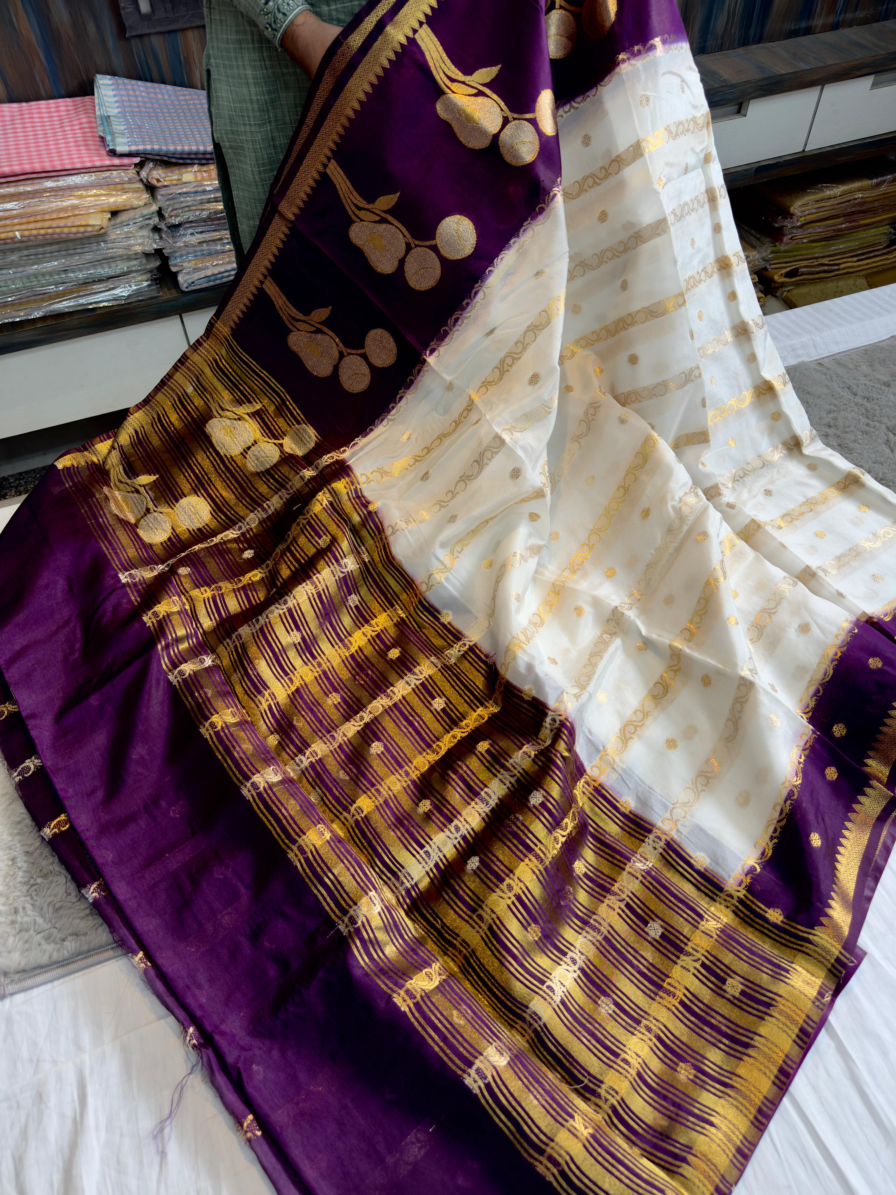 Purple and gold saree with white fabric underneath on a surface.
