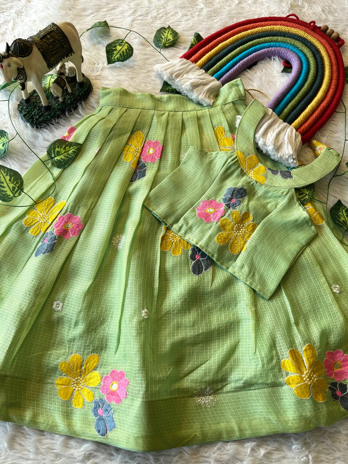 Pista dress with floral embroidery on a textured surface with decorative elements.