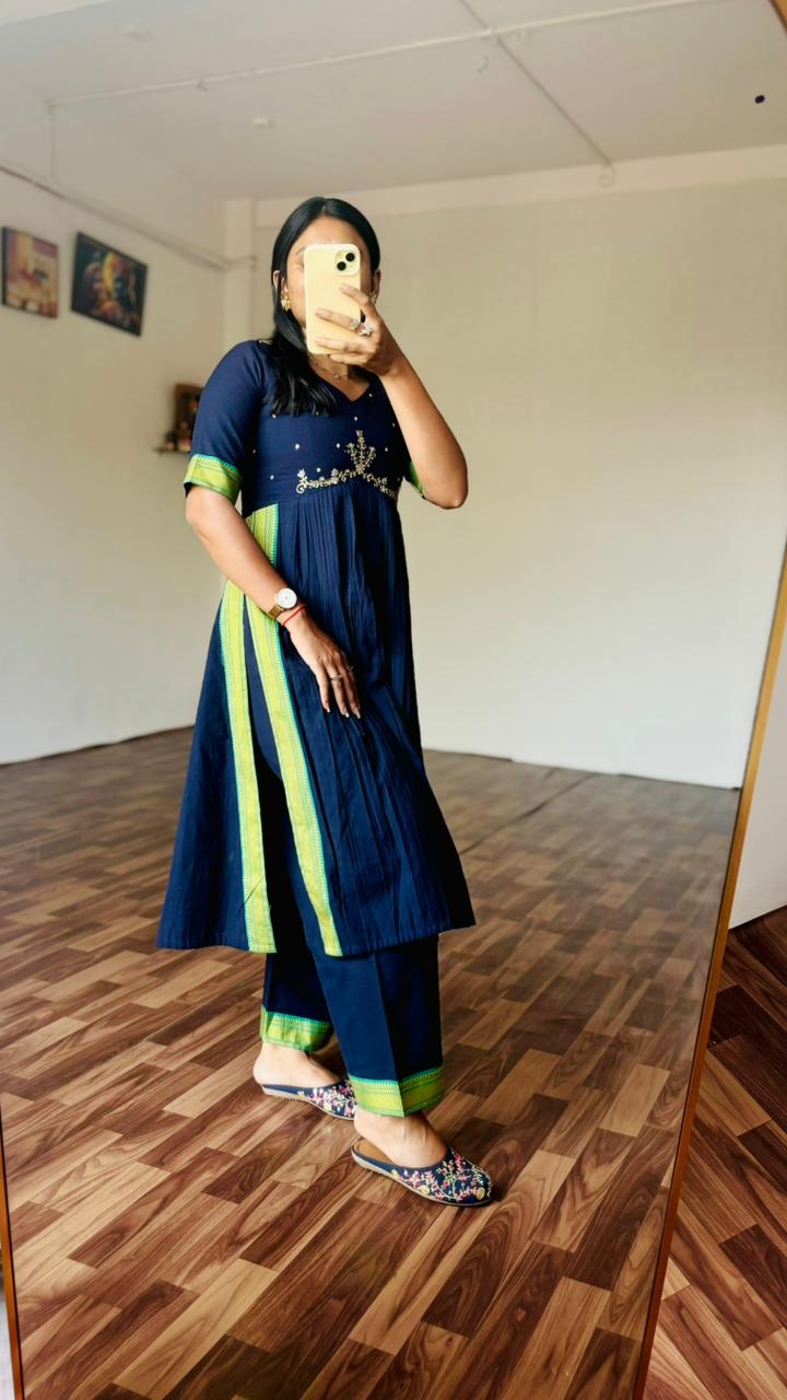 Person wearing a Navy blue and green outfit taking a mirror selfie.