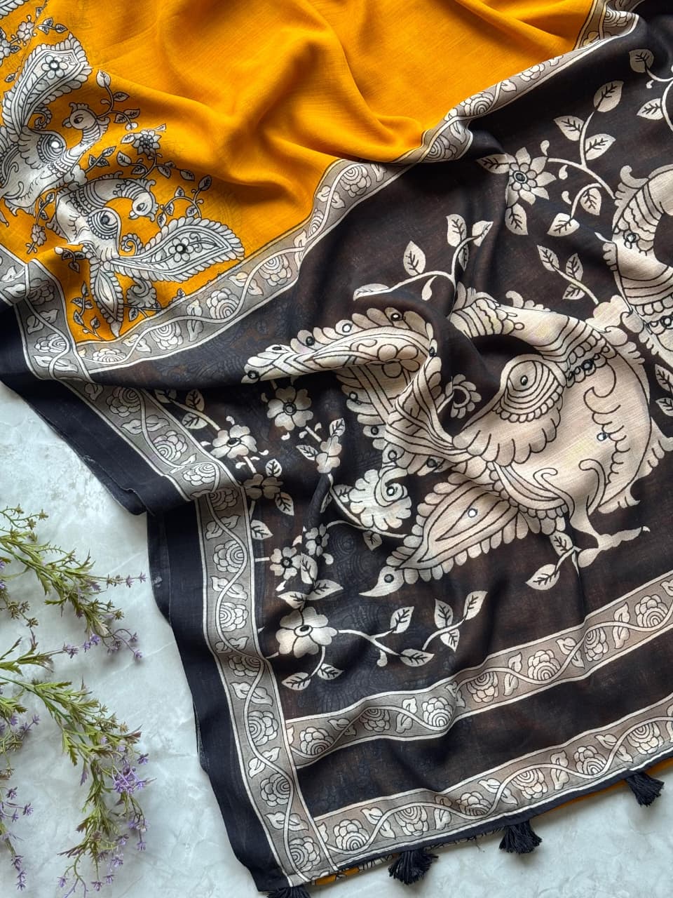 Two patterned scarves, one yellow and one black with white designs, on a light background.