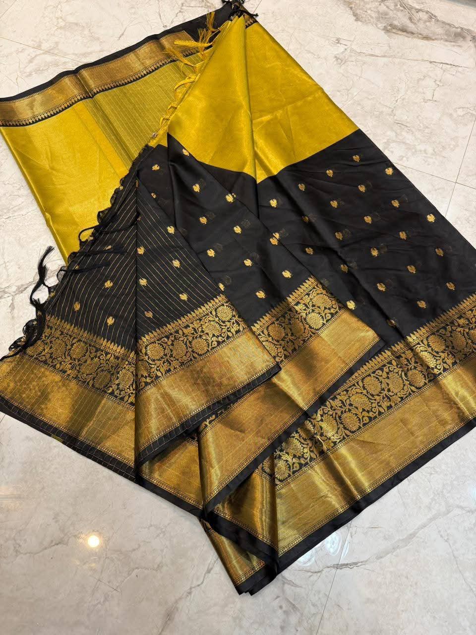 Black and gold saree with intricate patterns on a marble floor