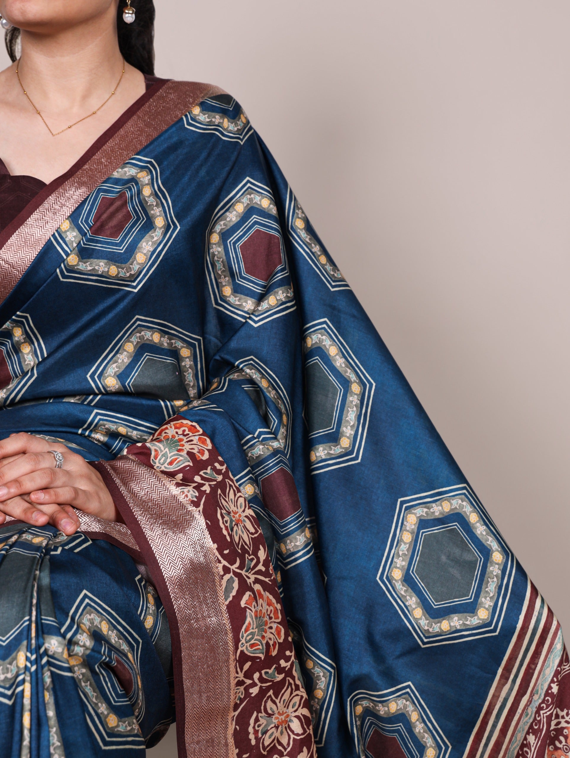 Woman wearing a blue 2 saree with intricate patterns on a plain background
