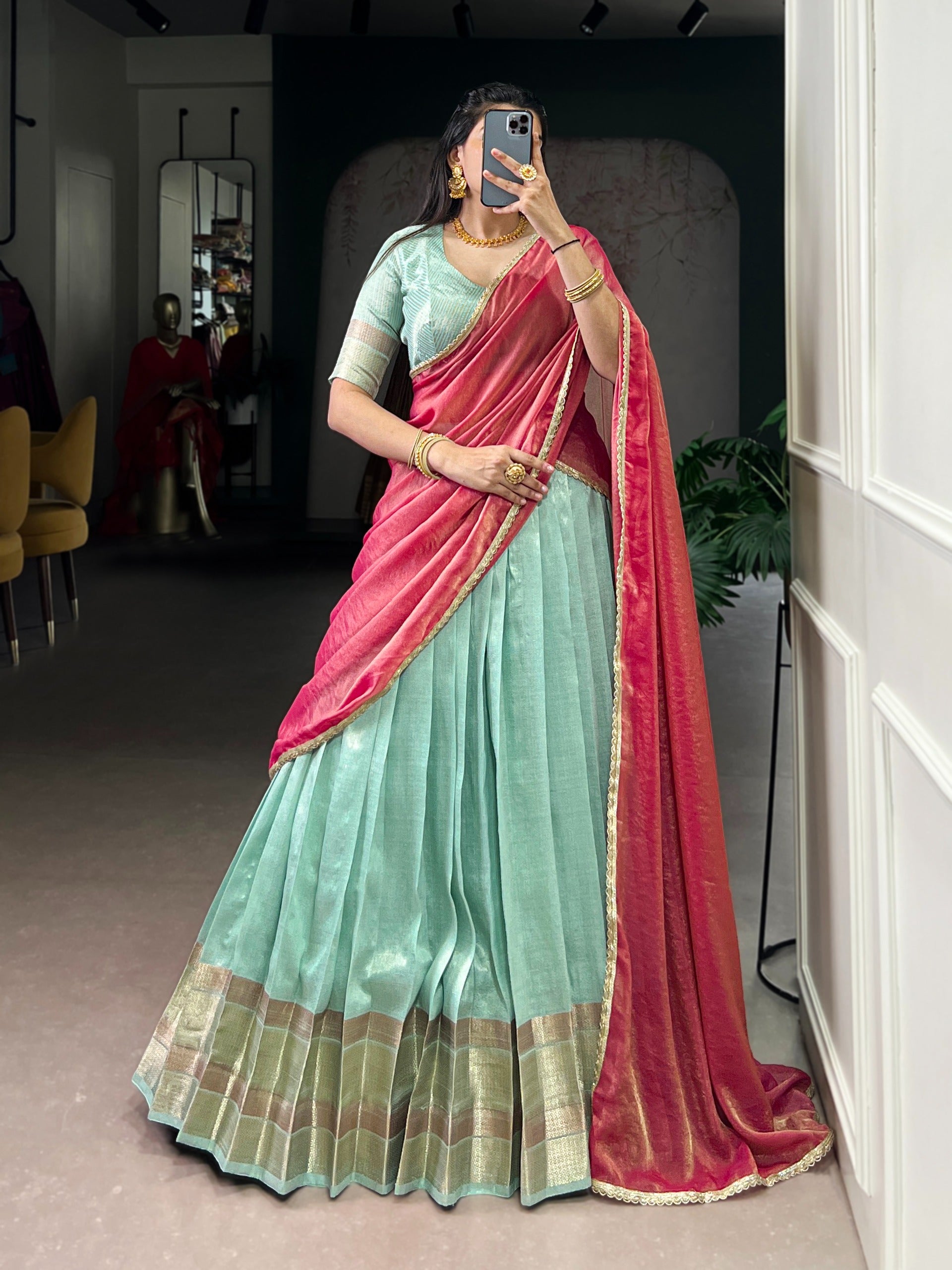 Woman wearing a Turquoise Blue saree with a pink border, standing indoors.