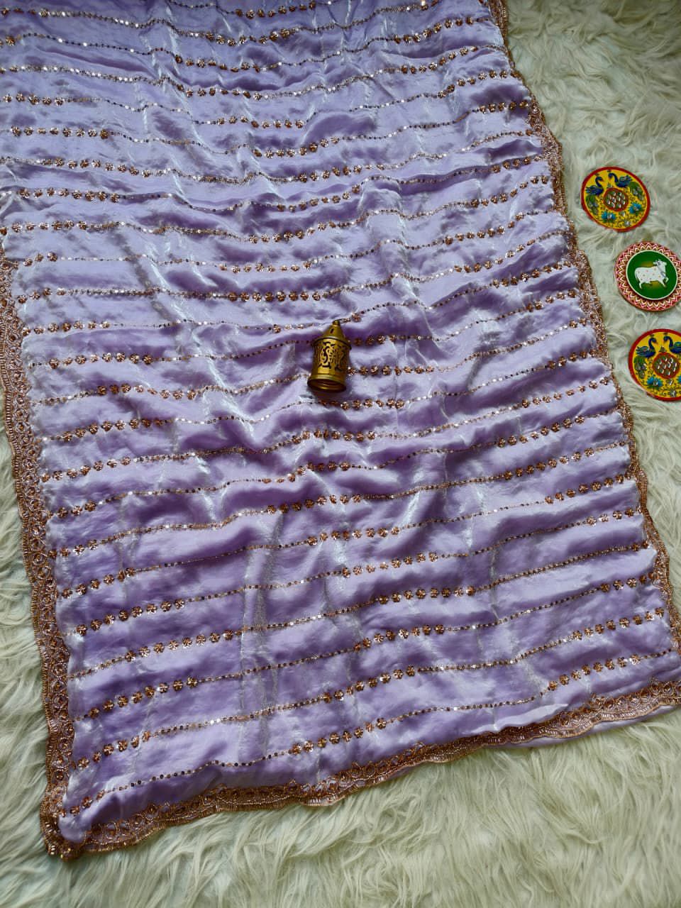 Lavender fabric with a small bottle and decorative items on a  surface