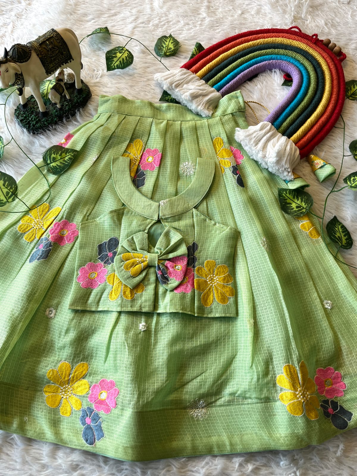 Pista dress with floral and bow details on a textured surface with decorative elements.