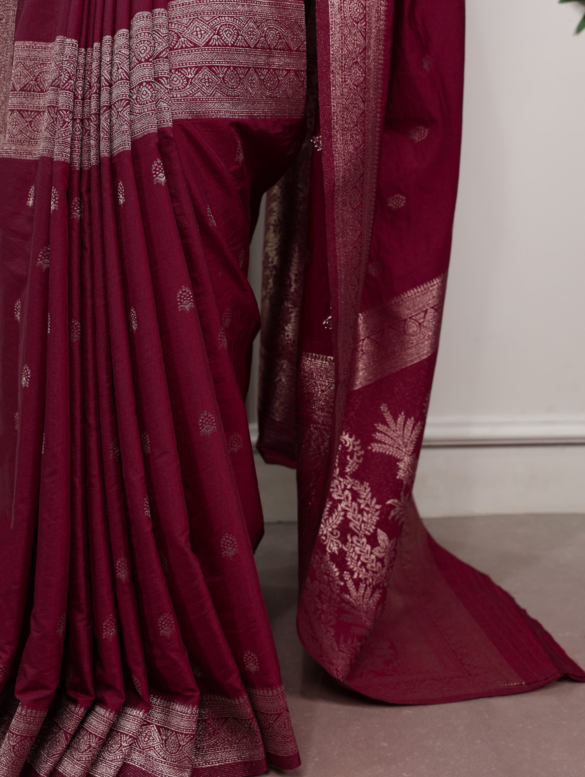 Maroon saree with white patterns on a neutral background