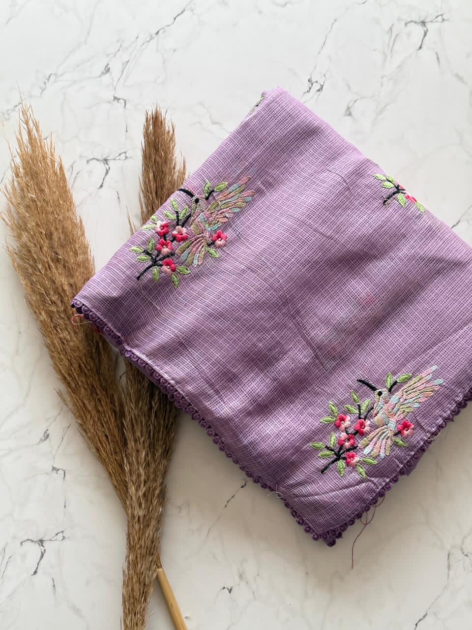 Lavender embroidered cloth with floral designs on a marble surface
