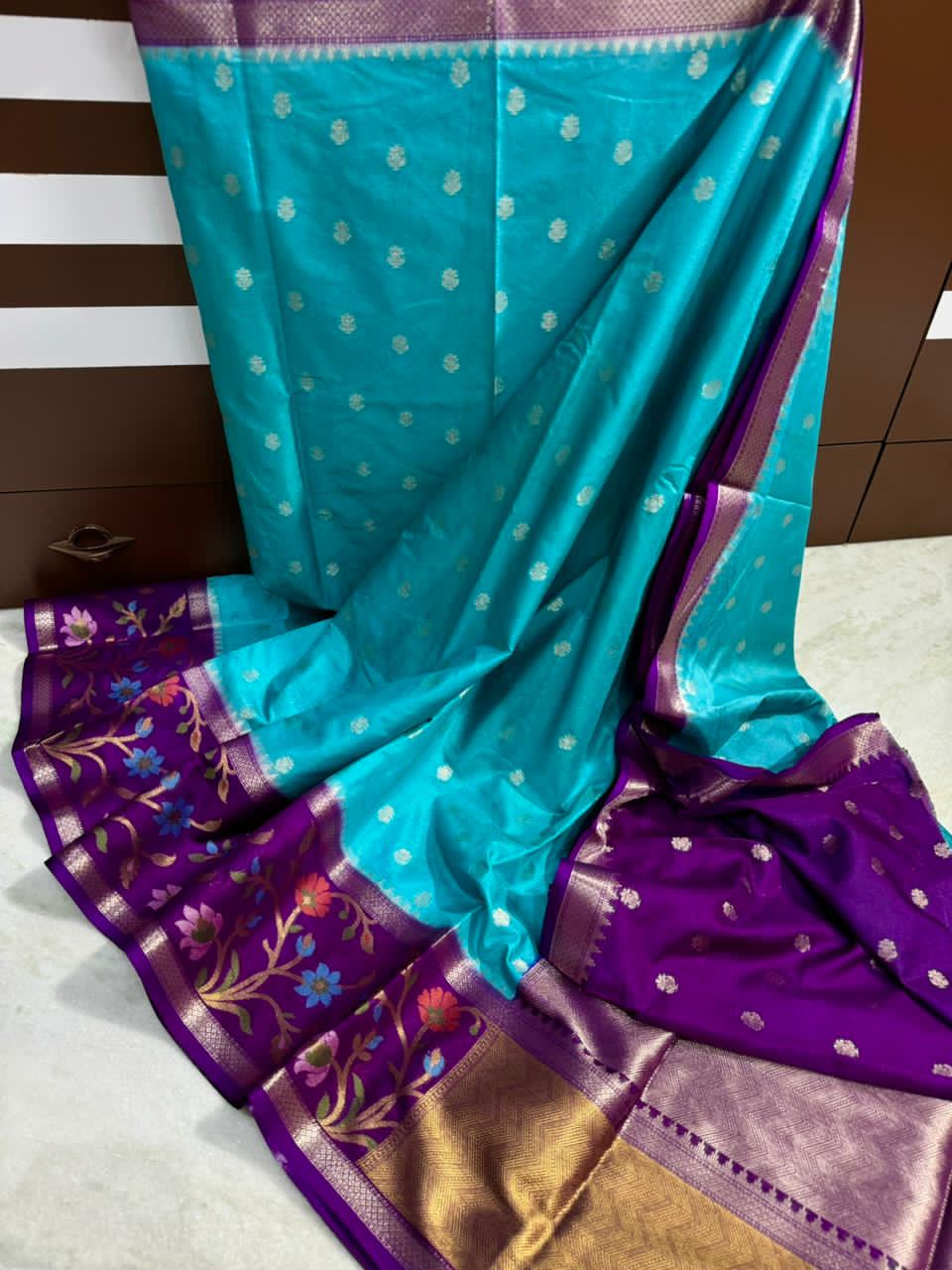 Sky Blue saree with floral patterns on a wooden surface