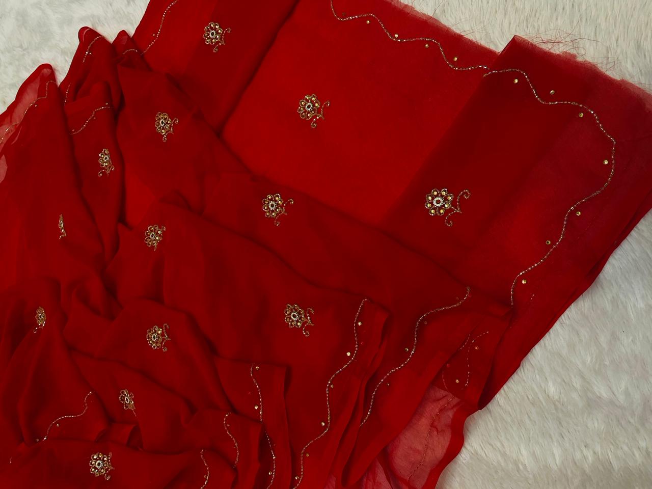 Red fabric with intricate gold embroidery on a white surface