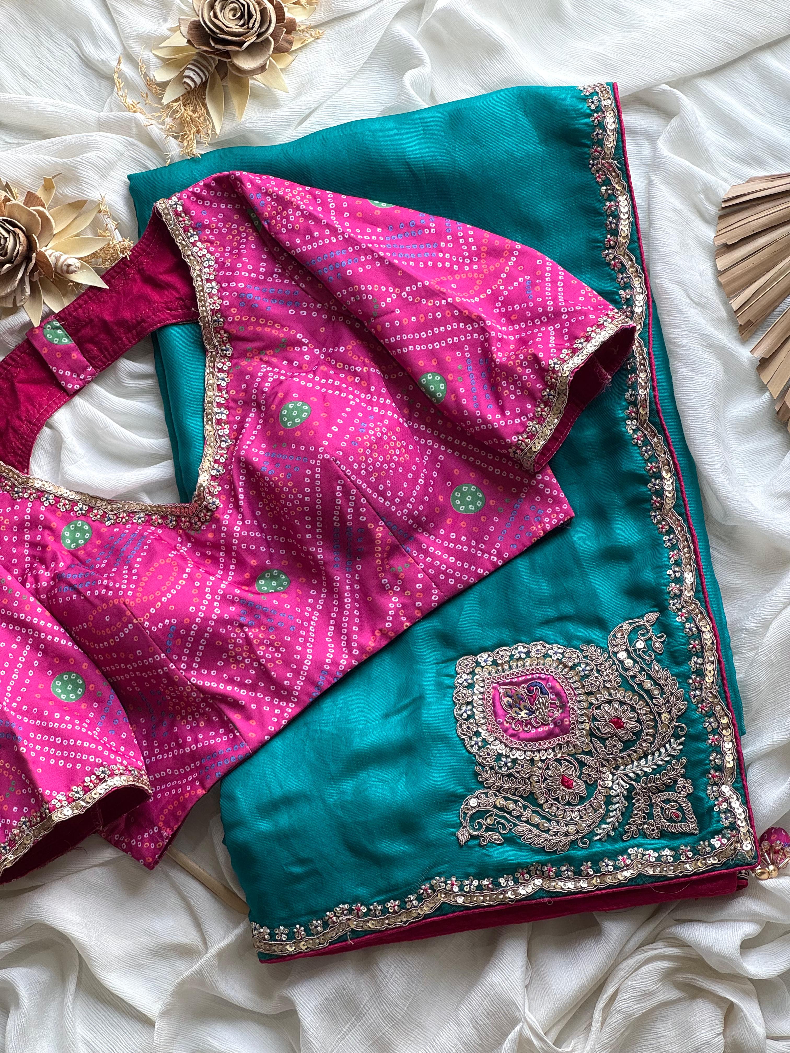 Teal blue and pink saree with intricate patterns on a white fabric background