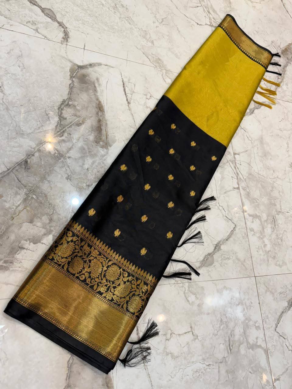 Black and gold saree with decorative patterns on a marble floor