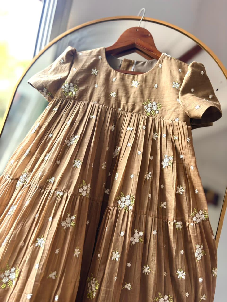Chiko dress with floral patterns on a hanger in front of a mirror.