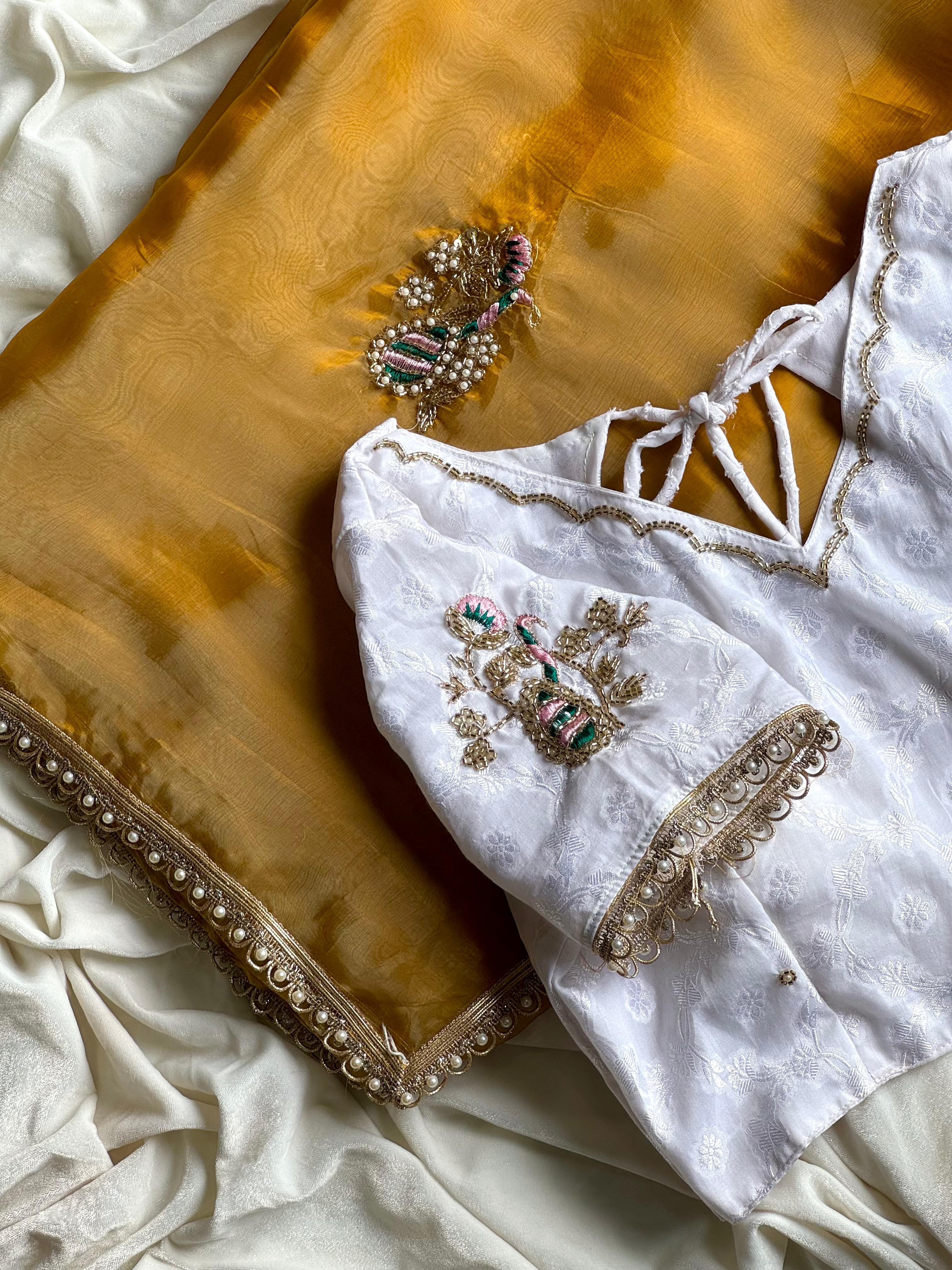 White embroidered blouse with mustard Yellow fabric detailing on a textured surface